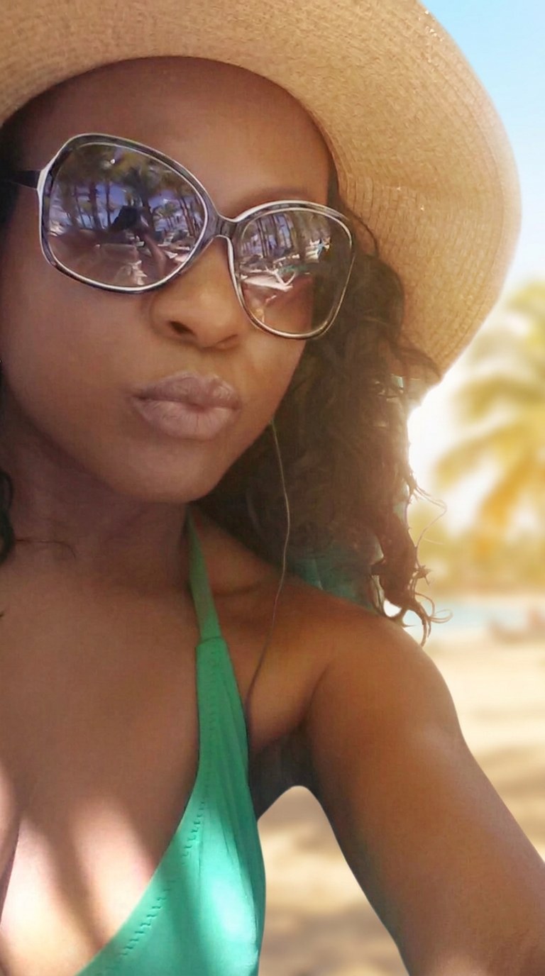 Jenn wearing a wide-brim straw hat and sunglasses at the beach